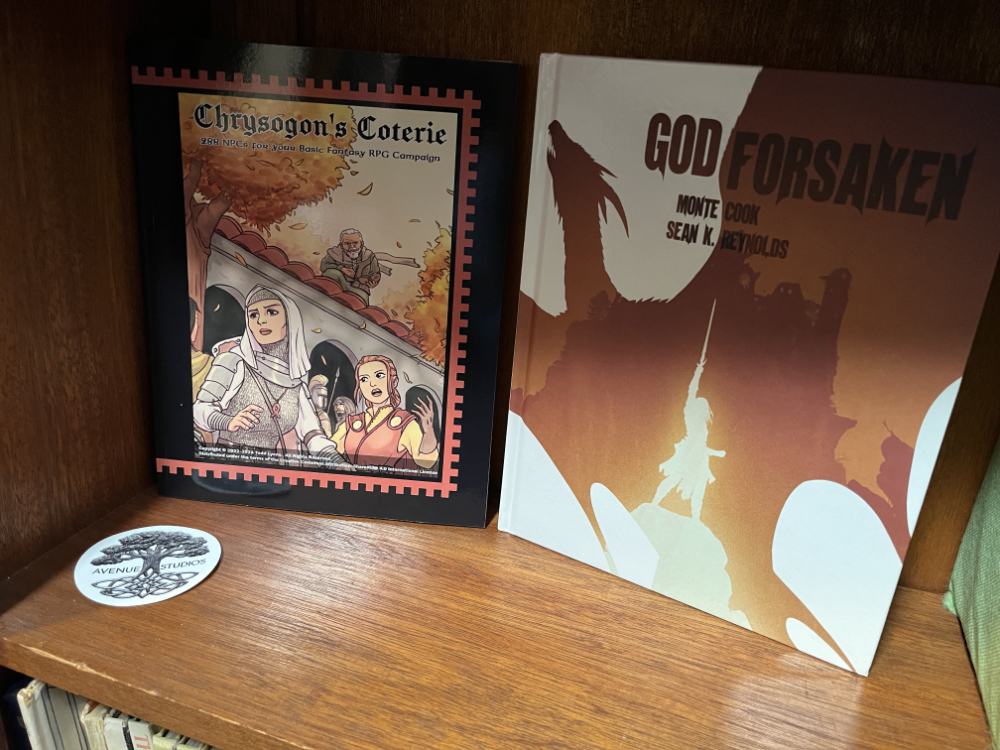 Part of my bookshelf, displaying Crysogon’s Coterie and Godforsaken